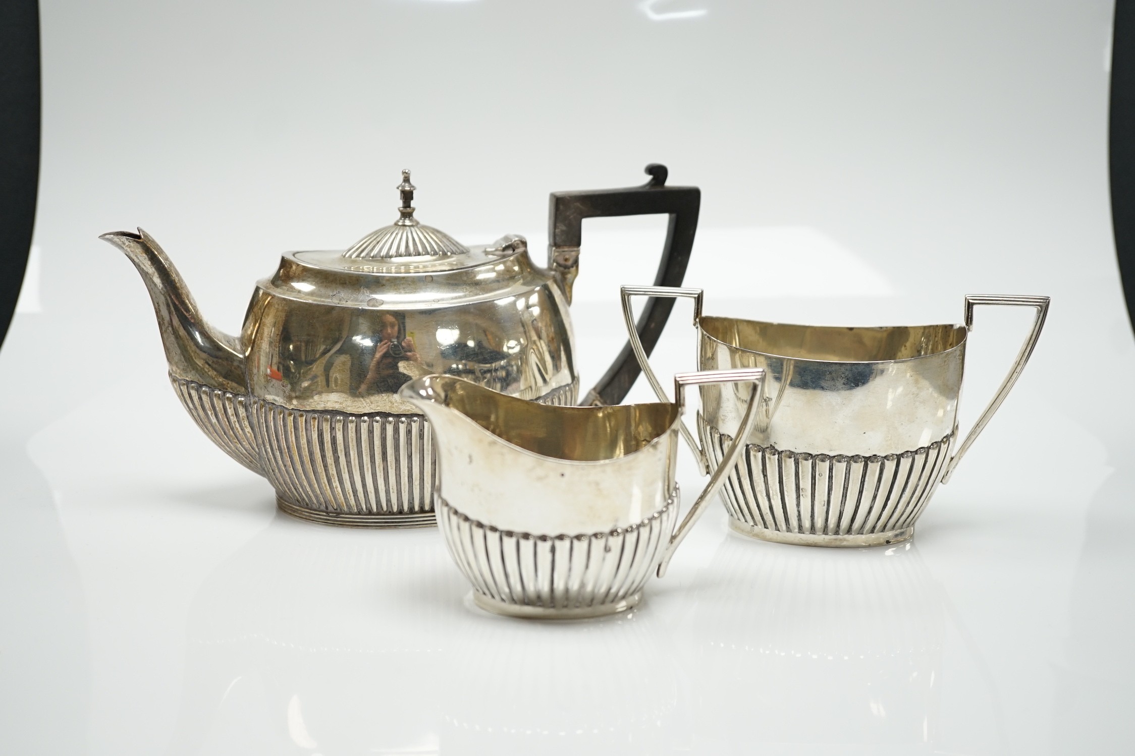 A matched early 20th century silver bachelor's three piece tea set, tea pot, James Dixon & Sons, Sheffield, 1920, cream and sugar, Walker & Hall, Sheffield, 1904, gross weight 14oz.